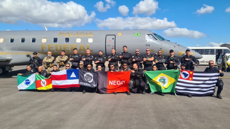 Agentes pousam para foto, diante de avião